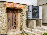 Air source heat pump installed outside an old renovated stone house, providing an energy-efficient low-carbon heating system.