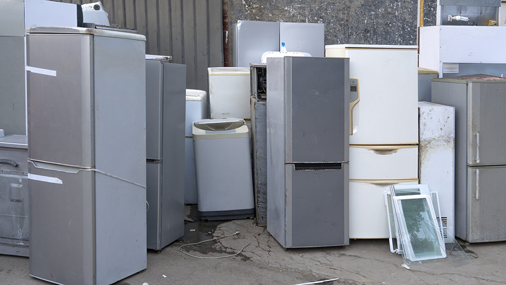Old refrigerators and freezers stacked at a recycling centre, awaiting collection and processing for disposal and recycling.