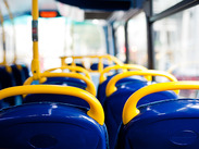 Empty blue bus seats with yellow handholds inside a public bus, showing passenger seating and aisle access.