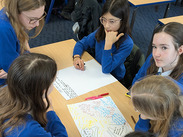 Selwood Academy pupils in school uniform sat around a table with white paper with notes on it.