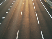 Empty multi-lane road with white lane markings in warm evening sunlight.