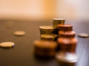 Stacks of assorted coins on a table with scattered change in the foreground.