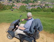 Person using an off-road mobility scooter on a hillside path at Ham Hill Country Park, overlooking the surrounding countryside.