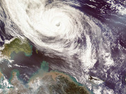 Satellite view of a powerful tropical cyclone with a defined eye, spiralling cloud bands and nearby coastal islands.