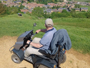 Person using an off-road mobility scooter on a hillside path at Ham Hill Country Park, overlooking the surrounding countryside.