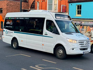 Somerset Council shuttle bus travelling through a town centre street, providing local public transport connections.