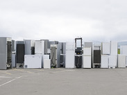 Rows of discarded fridges and freezers stacked at a recycling facility, ready for processing and materials recovery.