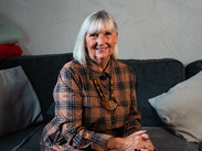 Kinship carer Valerie sits smiling on a sofa at home, sharing her story during Kinship Care Week in Somerset.