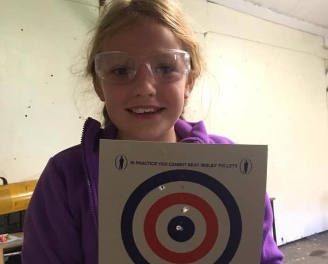 Young girl wearing safety goggles holding a target sheet