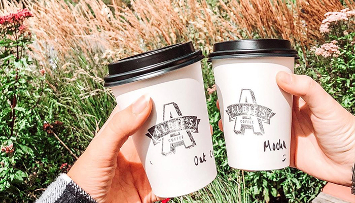 Two take out coffee cups being held together