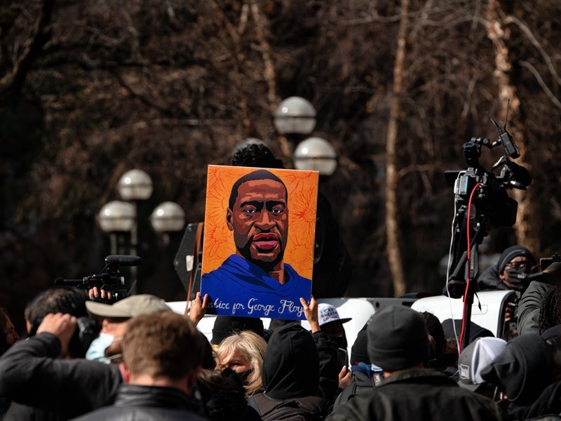 A crowd holding up and image of George Floyd