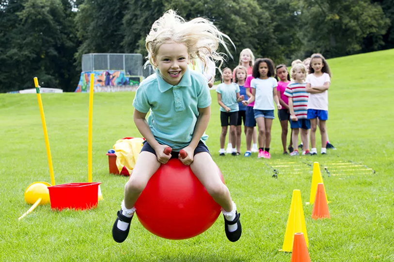 child bouncing on an orange hopper in a  park