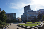Sheffield Peace Gardens in the sun. wedge lawns are visible, a few people sitting on the side of the water rills. 