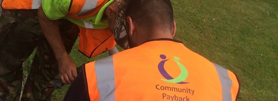 Close up of two men in high vis jackets leaning over and doing work in an allotment, no faces are visible