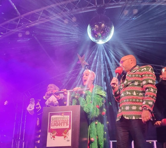 Jamie Campbell dressed in a Christmas tree dress with the Lord Mayor of Sheffield press the plunger to turn on Sheffield's Christmas lights
