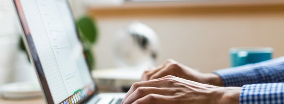 image of a hand typing on a laptop