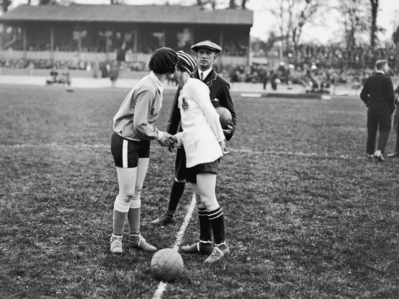 2 female football players greet each other with a kiss before they kick off