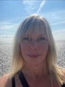 Photo of Helen Sanders.  Shoulder length straight blond hair.  Beach and blue sky in the background