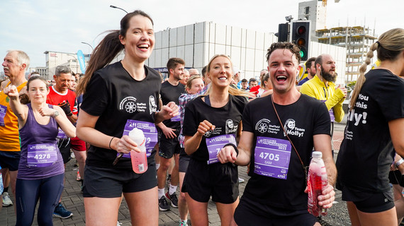 A group of people on Arundel Gate in front of the starting line smiling and excited about the race, with the O2 Academy in the background.