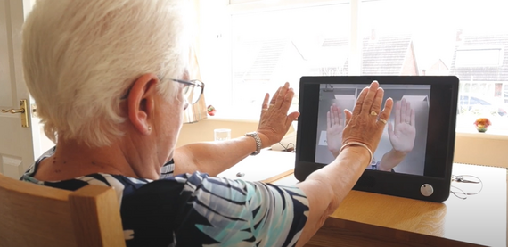 Woman doing arm exercises in front of a screen with remote support