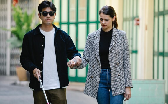 man with visual impairment guided by woman