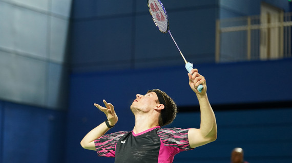 Para badminton player in a black and pink top swinging a badminton racquet