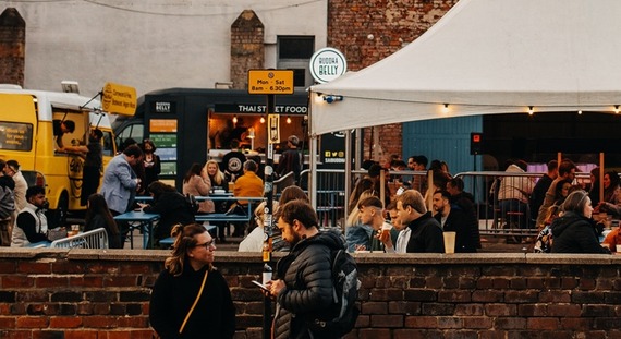 People socialising outside under white gazebos at Peddler Market