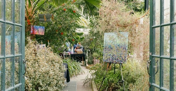 Artwork displayed in the pavilion of Sheffield Botanical Gardens, surrounded by various trees and flowers.