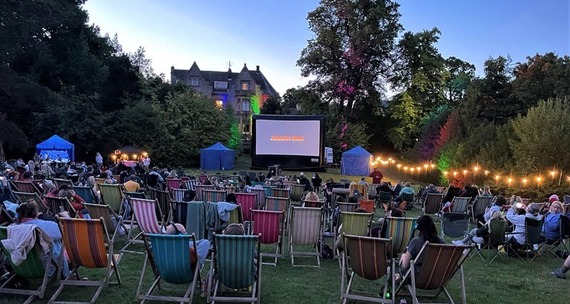 People sat on deckchairs enjoying a film surrounded by illuminated trees at the grounds of Kenwood Hall Hotel