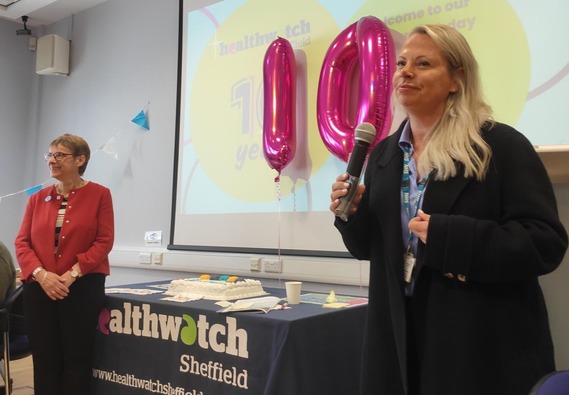 Judy Robinson Healthwatch Sheffield and Emma Latimer, NHS stand either side of a table topped by a screen and two pink balloons in the numbers 10