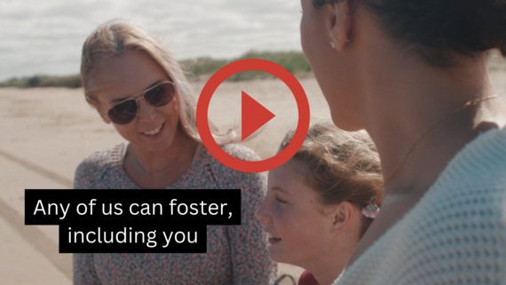 Two adults and a child stand happily together on a beach. Wording reads any of us can foster, including you. A red play button in the middle
