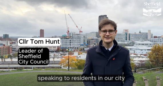 Cllr Tom Hunt standing against a view of Sheffield city centre