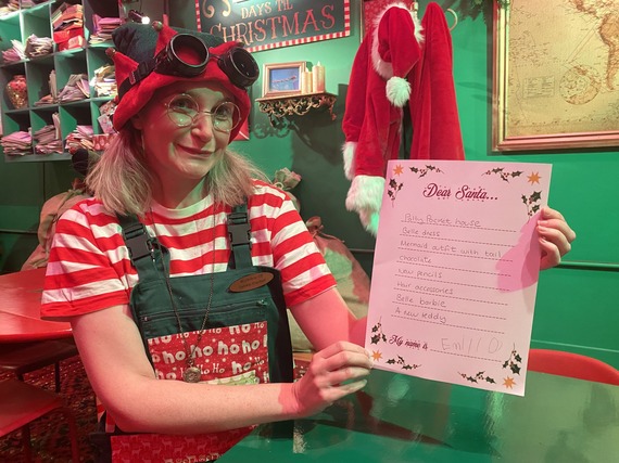 A Christmas elf holding up a Christmas wish list
