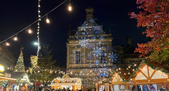 Christmas market stalls with snowflakes projected brightly onto the Town Hall