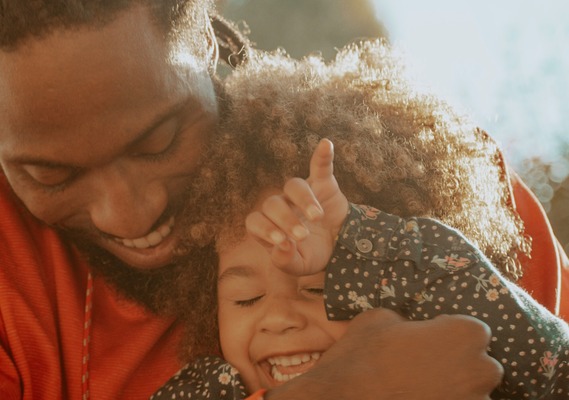 A person wearing a red jumper is holding a child against their chest.