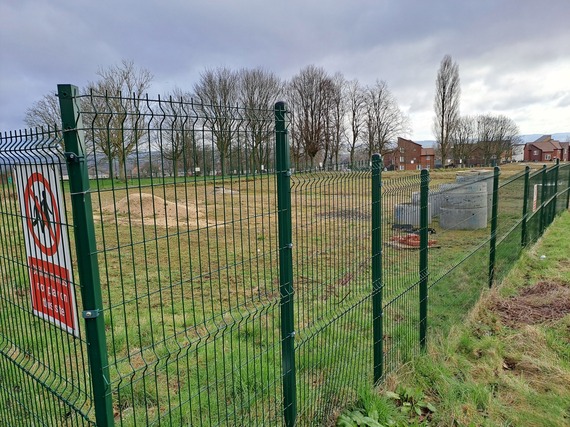 A view through a fence at the Newstead development site on a cloudy day with building materials on the ground