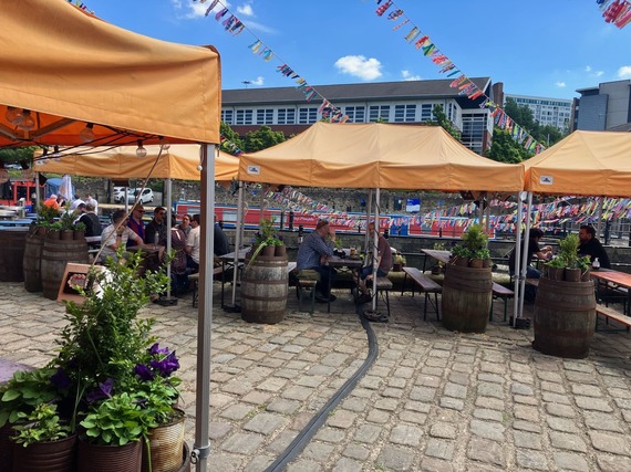 The canal-side Dorothy Pax beer garden on a sunny day, with bunting, planting, and canal boats