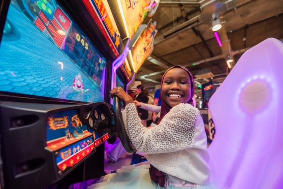 A happy young person wearing a headscarf is playing a driving game 