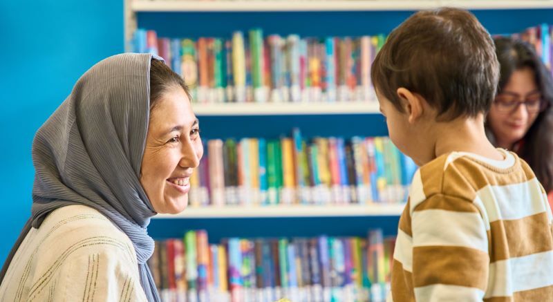 An adult smiling at a child inside a library