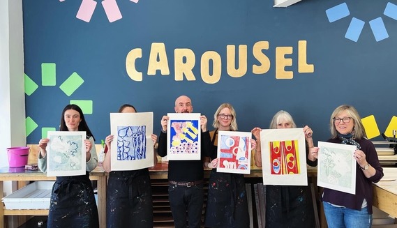 Carousel course attendees proudly hold up their work in the studio