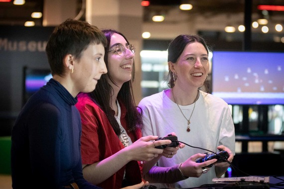 Three young people in NVM are enjoying playing video games