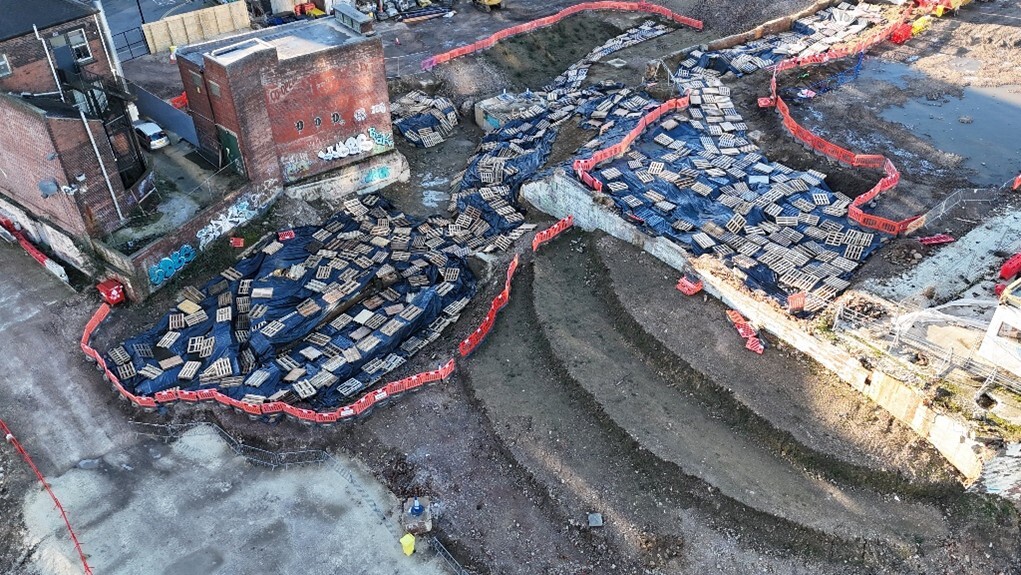 An aerial view of castle remains protected by blue covers.