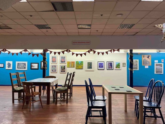 An indoor gallery space with chairs, tables, bunting, and pictures lining the walls