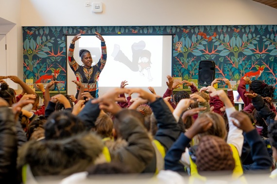 A person demonstrating a ballet position to an audience as they join in