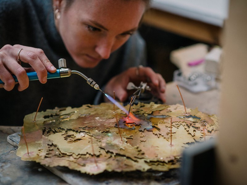 An artist adding to her artwork in her studio