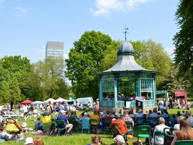 A crowd surrounding the bandstand in Weston Park on a sunny day