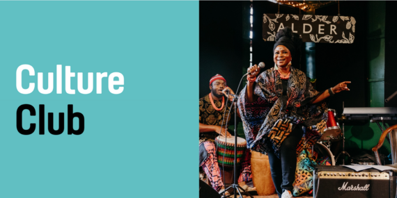 black woman in traditional african garms singing on a stage in a pub
