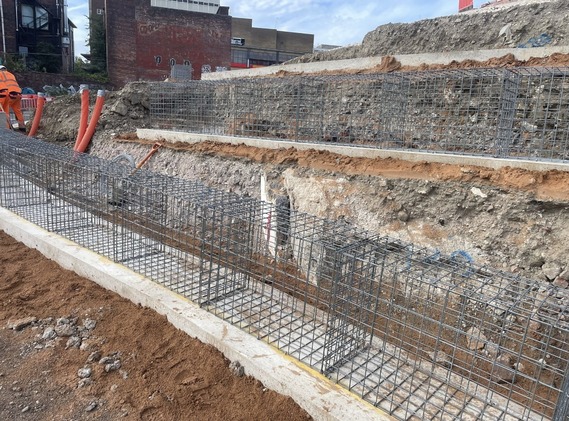 Empty steel baskets lined up among the tiered rock on the castle site
