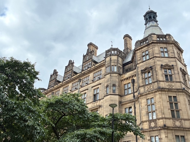 Sheffield Town Hall viewed from Pinstone Street, with large trees overlapping on the left.