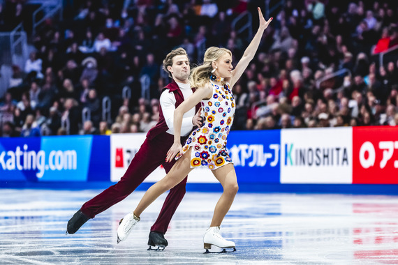 Two figure skaters performing on an ice rink during a competition.